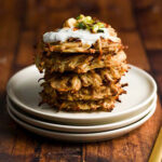 a stack of 5 potato latkes with sour cream and chives